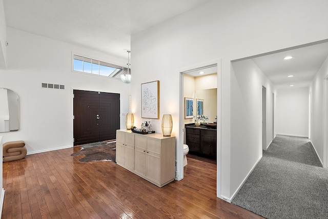 foyer entrance with baseboards, visible vents, dark wood-type flooring, and recessed lighting