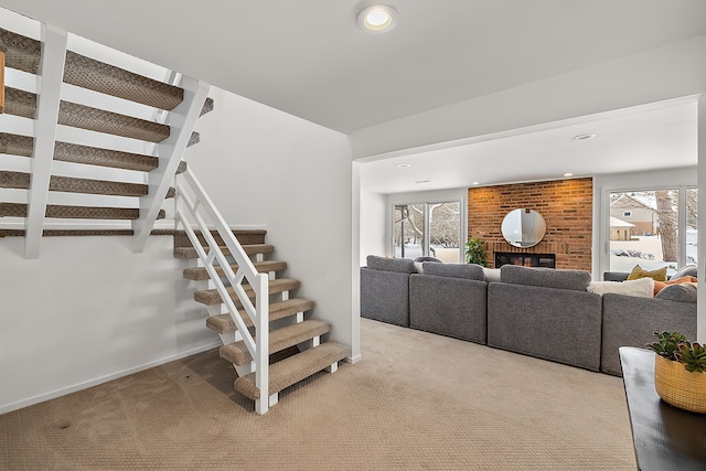 stairway featuring carpet floors, a wealth of natural light, a brick fireplace, and recessed lighting