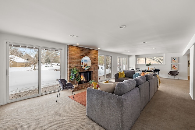 living room featuring light carpet, a fireplace, visible vents, and a wealth of natural light