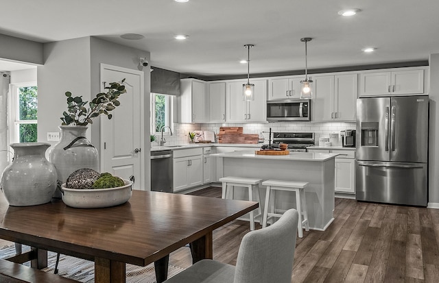 kitchen with stainless steel appliances, hanging light fixtures, a wealth of natural light, and white cabinets