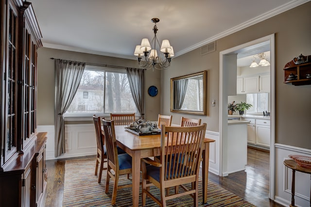 dining room with an inviting chandelier, crown molding, and dark wood-type flooring