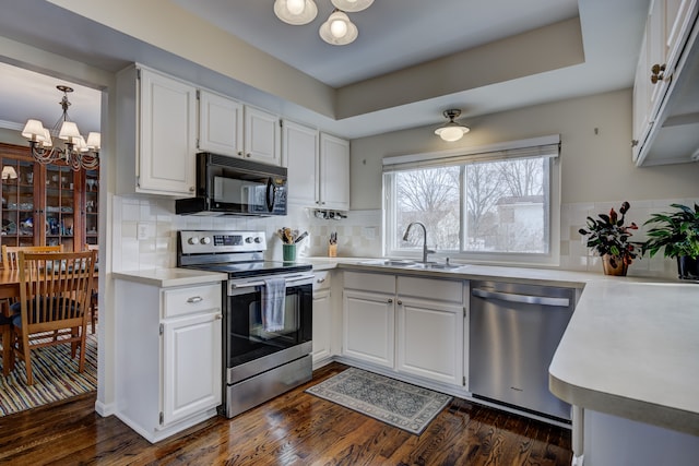 kitchen with white cabinetry, appliances with stainless steel finishes, sink, and a notable chandelier