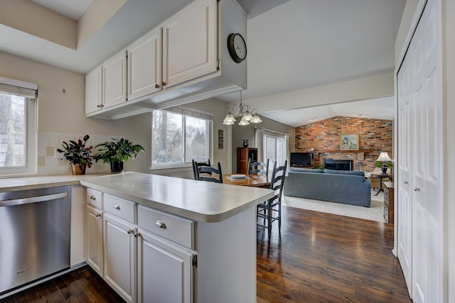 kitchen featuring a fireplace, white cabinetry, dishwasher, lofted ceiling, and kitchen peninsula