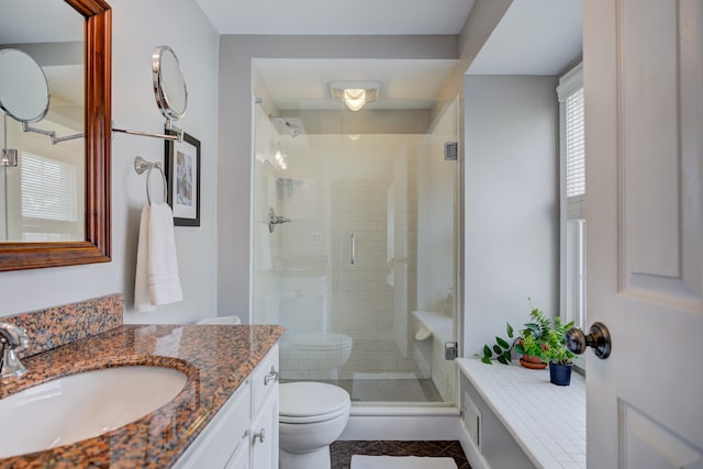 bathroom with walk in shower, vanity, and toilet