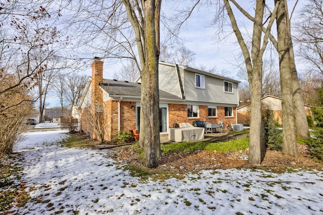 snow covered back of property featuring central AC