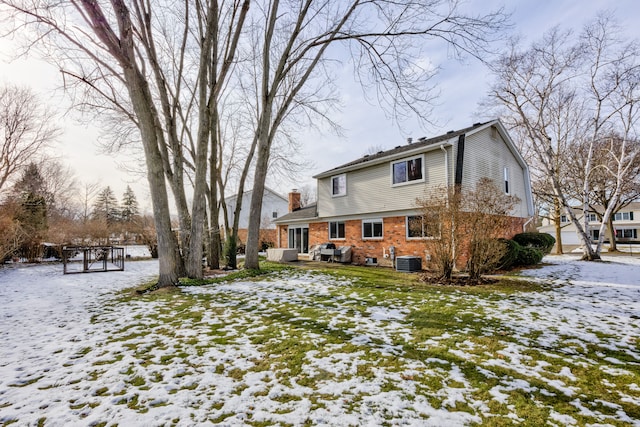 snow covered back of property featuring central AC unit