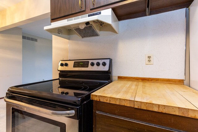 kitchen with stainless steel range with electric stovetop, wooden counters, and dark brown cabinets