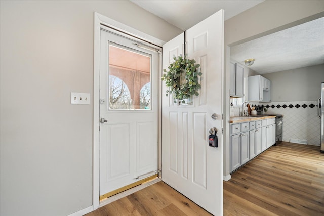 entryway with sink, tile walls, and light wood-type flooring