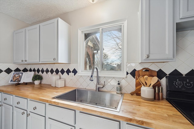 kitchen with tasteful backsplash, sink, a textured ceiling, and wood counters