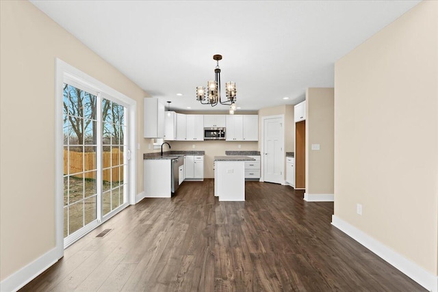 kitchen with appliances with stainless steel finishes, white cabinetry, sink, a center island, and dark wood-type flooring