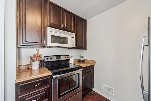 kitchen featuring electric stove, fridge, dark brown cabinetry, and dark wood-type flooring