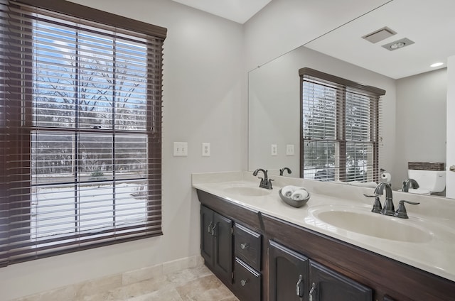 full bath featuring double vanity, baseboards, and a sink