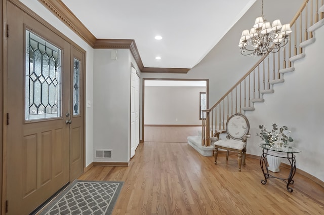 foyer entrance with ornamental molding, a chandelier, and light hardwood / wood-style flooring