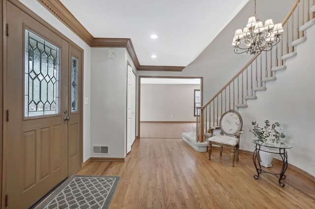 foyer featuring light wood-type flooring, visible vents, stairs, and ornamental molding