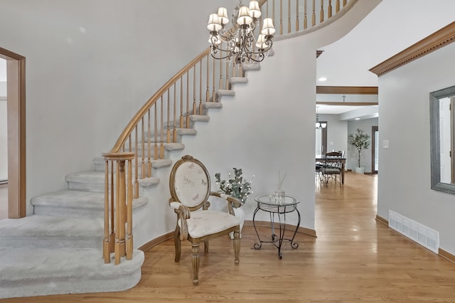 staircase with wood-type flooring and a chandelier