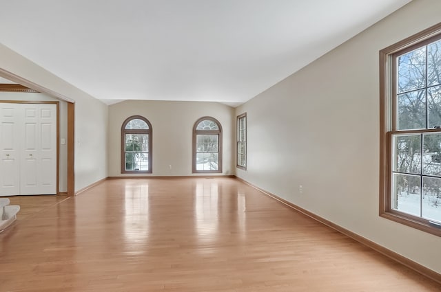 spare room with lofted ceiling and light hardwood / wood-style flooring