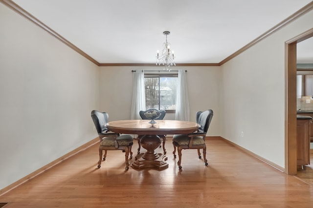 dining area with light wood-type flooring, baseboards, a notable chandelier, and crown molding