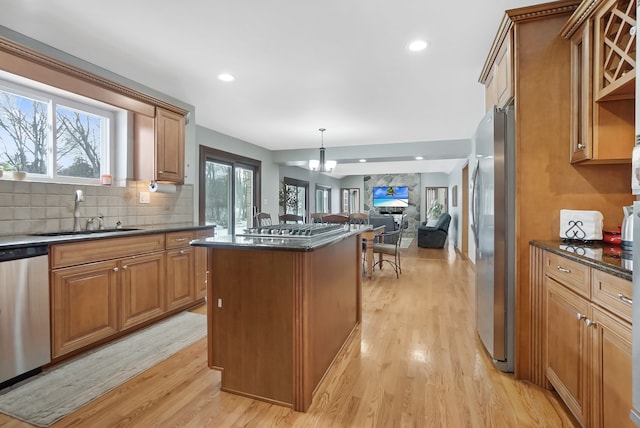 kitchen featuring light wood-type flooring, stainless steel appliances, sink, and dark stone countertops