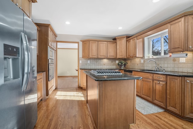 kitchen with stainless steel appliances, a center island, sink, and dark stone counters