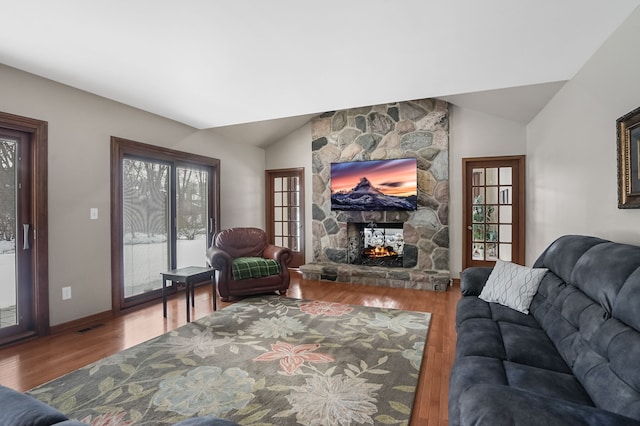 living room featuring lofted ceiling, a fireplace, and wood-type flooring