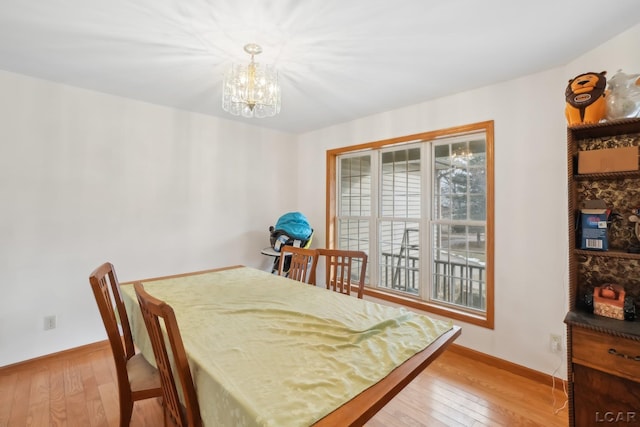 dining space with light hardwood / wood-style flooring and a chandelier