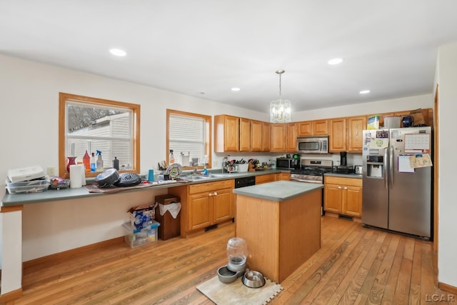 kitchen with sink, a center island, hanging light fixtures, light hardwood / wood-style flooring, and stainless steel appliances