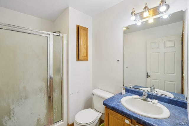 bathroom featuring a shower with door, vanity, and toilet