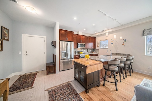 kitchen featuring a breakfast bar, pendant lighting, sink, decorative backsplash, and stainless steel appliances