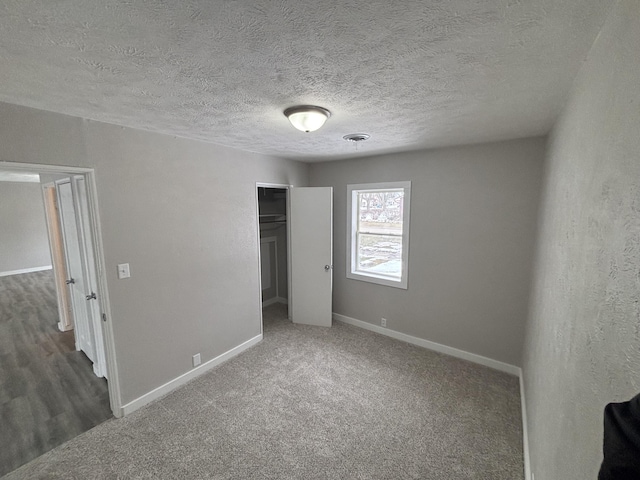 unfurnished bedroom with a textured ceiling, a closet, and dark colored carpet