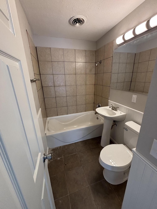 full bathroom featuring sink, a textured ceiling, tile patterned floors, toilet, and tiled shower / bath