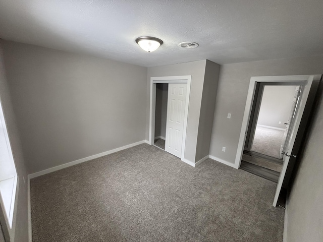 unfurnished bedroom featuring dark carpet, a closet, and a textured ceiling