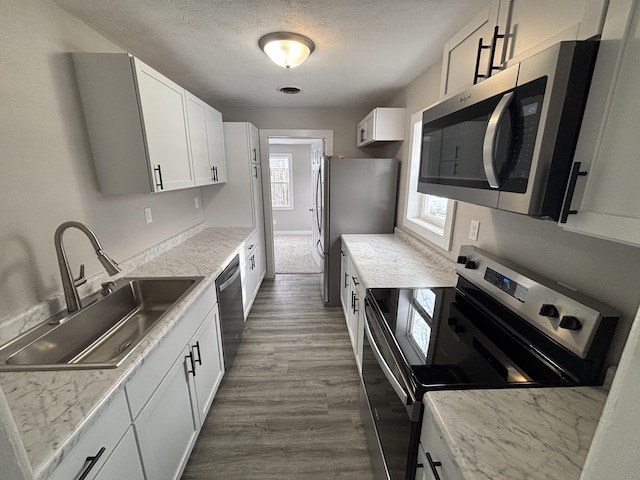 kitchen featuring sink, stainless steel appliances, dark hardwood / wood-style floors, a textured ceiling, and white cabinets