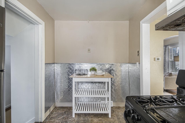 interior space with tile walls, stainless steel fridge, and gas range oven