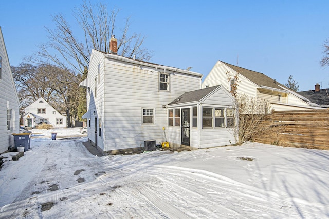 snow covered house featuring a sunroom