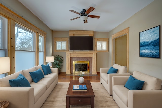 living room with a brick fireplace, light hardwood / wood-style floors, a healthy amount of sunlight, and ceiling fan