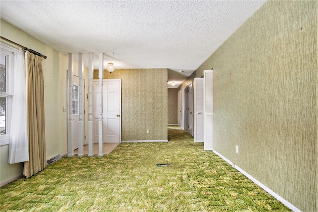 empty room with carpet floors and a textured ceiling