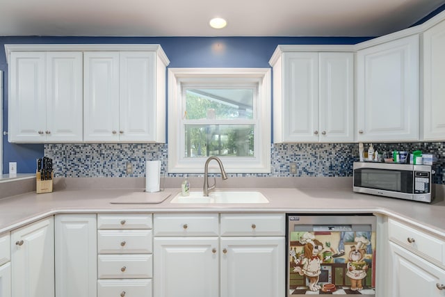 kitchen featuring sink, decorative backsplash, white cabinets, and dishwasher