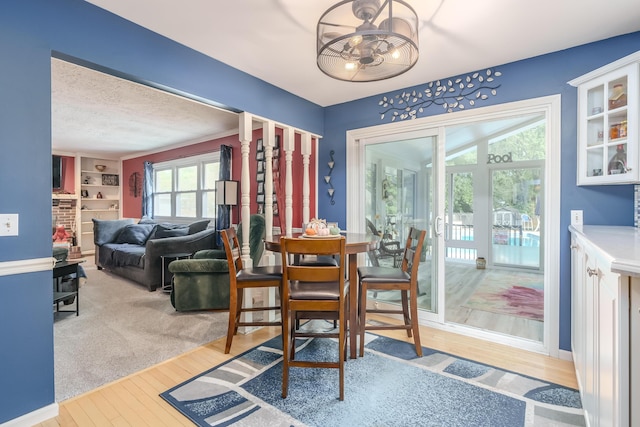 dining room with a textured ceiling, built in features, and light wood-type flooring