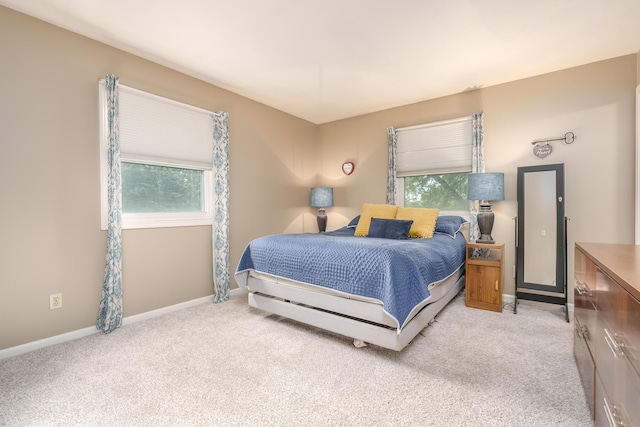 bedroom with light colored carpet and multiple windows