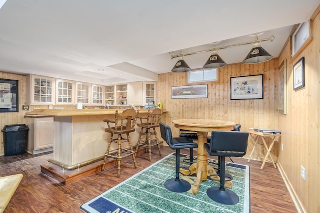 dining area with indoor bar, wood-type flooring, and wood walls