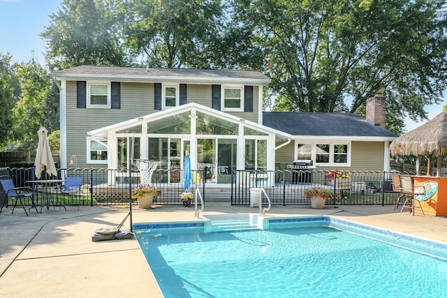 rear view of property with a fenced in pool, a patio, and a sunroom