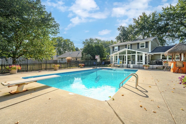 view of pool with a diving board and a patio