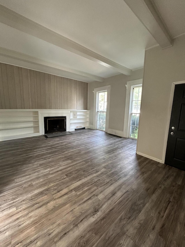 unfurnished living room featuring beam ceiling and dark hardwood / wood-style floors