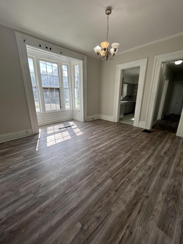 unfurnished dining area with dark hardwood / wood-style flooring, ornamental molding, and a chandelier