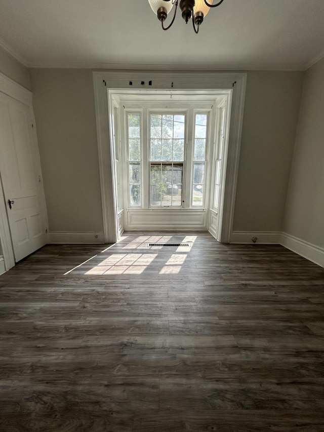 unfurnished room featuring ornamental molding, dark hardwood / wood-style floors, and an inviting chandelier