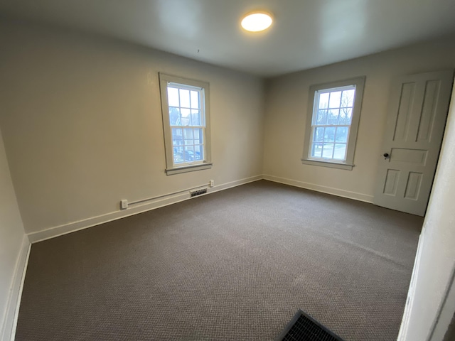 spare room featuring dark colored carpet