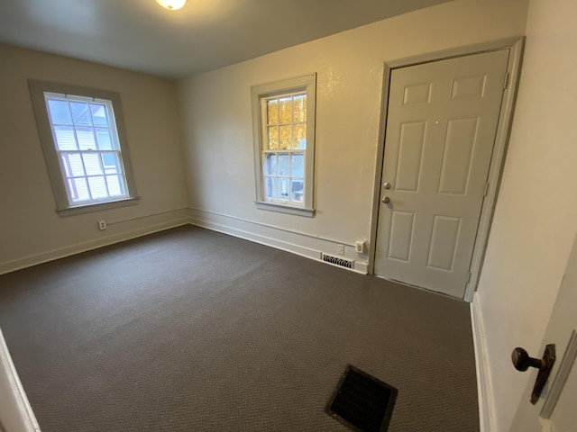 unfurnished room with dark colored carpet