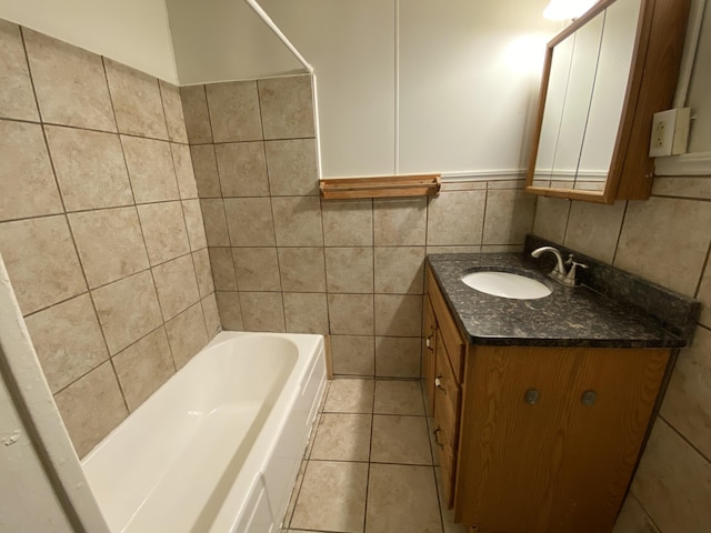 bathroom with tile walls, a bath, vanity, and tile patterned flooring