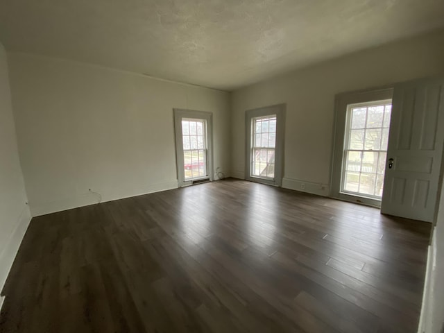 unfurnished room featuring dark wood-type flooring and a textured ceiling