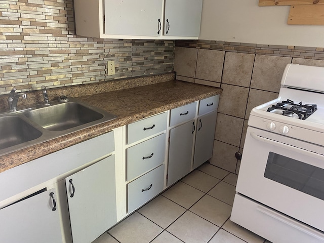 kitchen featuring light tile patterned flooring, sink, tile walls, white cabinets, and gas range gas stove